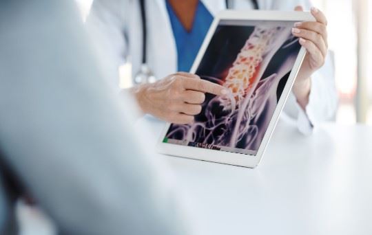 doctor showing x-ray of a spinal injury to patient