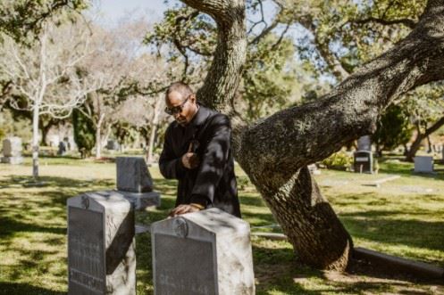 sad man standing at a graveside