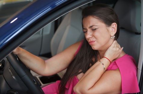 woman rubbing her neck in pain after car accident